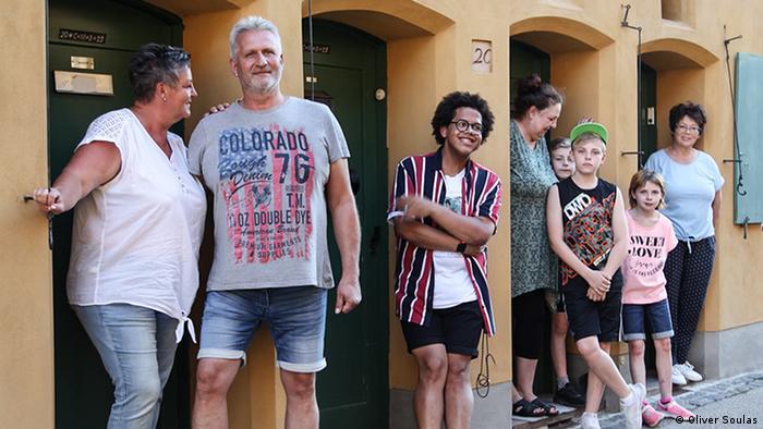 Noel Guobadia (center in striped shirt) stands with his neighbors outside their apartment doors in the Fuggerei housing estate