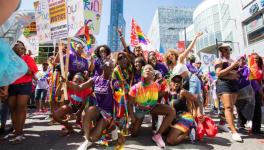 Participants in the pride march in Toronto with 'Fight for 15' placards.