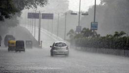 Vehicles move on the road during the heavy rainfall, in Surat on Sunday.