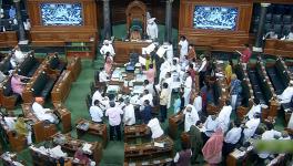 Opposition MPs holding placards stage a protest over inflation, 5% GST on essential items and other issues in the Well of Lok Sabha 