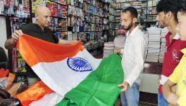 A vendor shows a tri-colour national flag to a customer "Har Ghar Tiranga" campaign ahead of next month's Independence Day celebrations at Mendhar area of Poonch