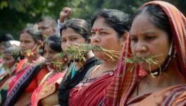 'Gaon Sathi' women workers put grass in their mouth as they stage a protest demanding hike in their monthly wages and to give them permanent status.