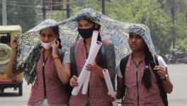 Students shield themselves from the heat with a scarf on a hot summer afternoon in Meerut, UP Image Courtesy: PTI
