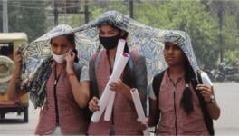 Students shield themselves from the heat with a scarf on a hot summer afternoon in Meerut, UP. Image Courtesy: PTI