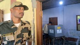 A security personnel stands guard as a voter casts his vote during the by-elections to Boxanagar assembly seat, in Tripura's Sepahijala district, Tuesday, Sept. 5, 2023.