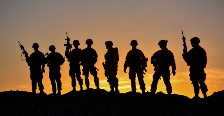 American soldiers in a remote post, silhouetted against the dimming Afghan sky.