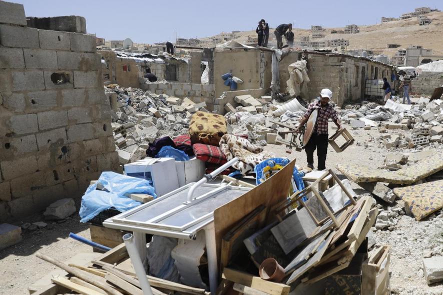 A Syrian man gathers his belongings as workers demolish cement block shelters at a refugee camp in the northeastern Lebanese town of Arsal, in the Bekaa valley