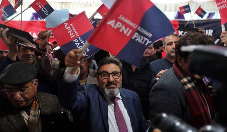 Former PDP leader Altaf Bukhari (center) waves the new party flag after launching Apni Party