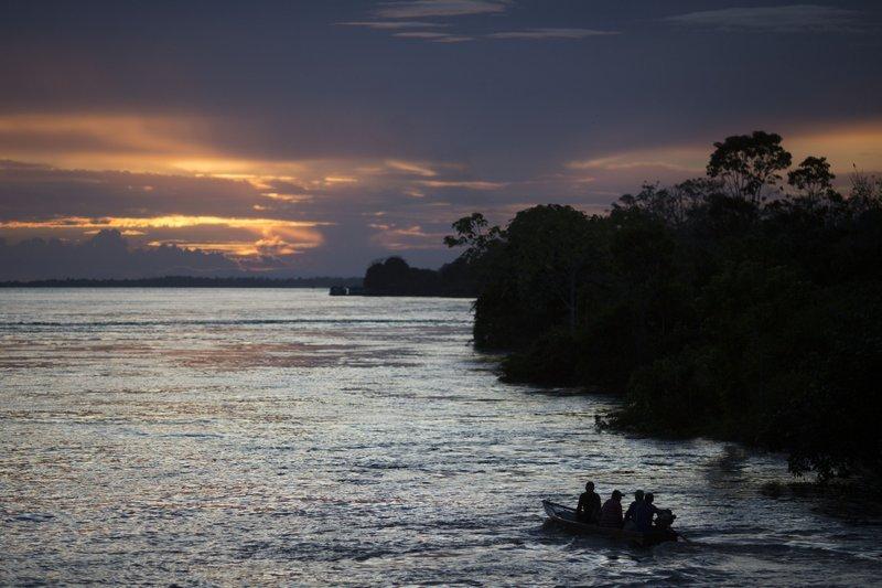 a small boat navigates on the Solimoes River near Manaus, Brazil. In the remote Amazon community of Betania, indigenous Tikuna tribe members suspect the new coronavirus arrived in May of 2020 after some returned from a two-hour boat trip down the Solimoes River to pick up their government benefit payments. 