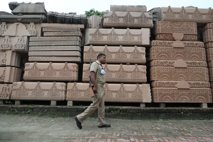 A policeman walks past the carved stones meant for temple construction. Photo by Sumit Kumar