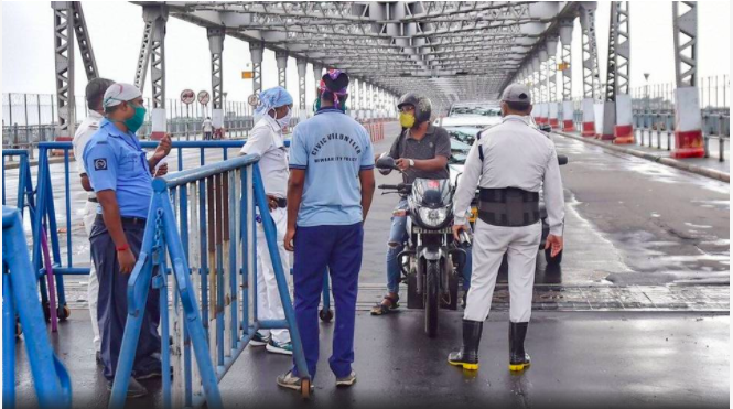 Police personnel stop commuters at Howrah Bridge, during the complete biweekly lockdown in the wake of coronavirus pandemic, in Kolkata.   | Photo Credit: PTI