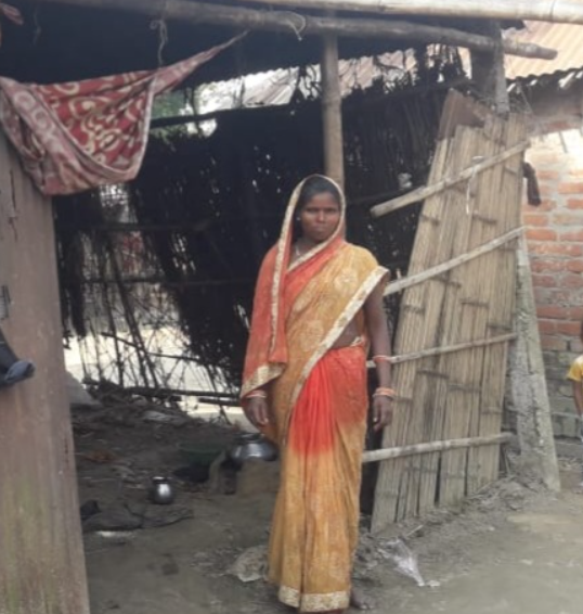Phekni Devi stand outside her thatch -bamboo house