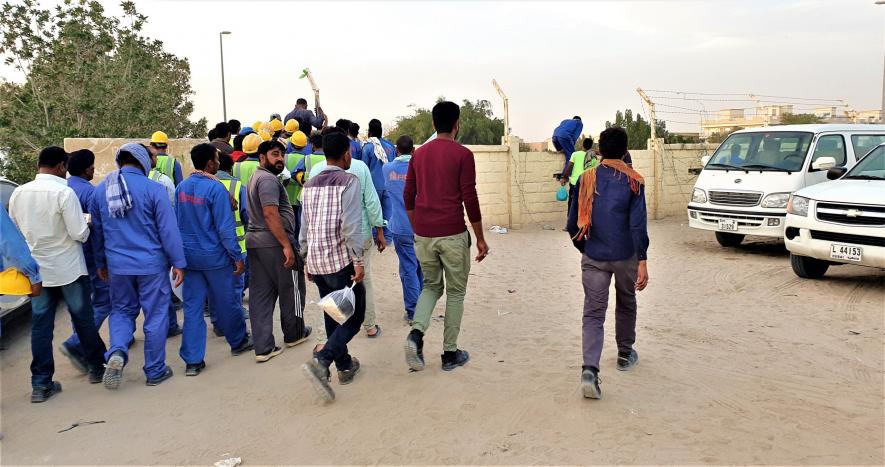 Migrant workers heading to camp from drop point in Sonapur, UAE.