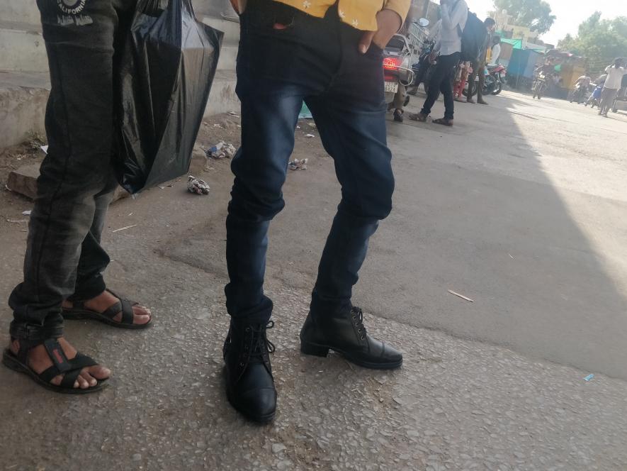 Return migrants trying on new shoes at the bus stand. 