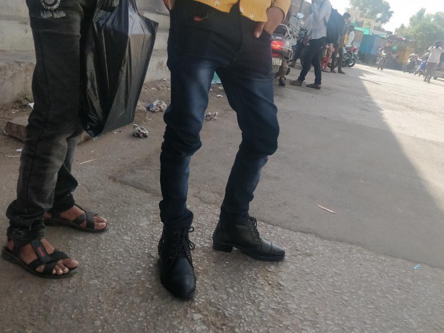 Return migrants trying on new shoes at the bus stand.