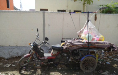 A motor tricycle for selling balloons parked aside since there are no sales.