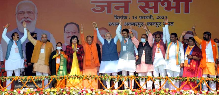 Kanpur Dehat, Feb 14 (ANI): Prime Minister Narendra Modi with Uttar Pradesh Chief Minister Yogi Adityanath and others raises hands at a public meeting, in Kanpur Dehat district of Uttar Pradesh on Monday. (ANI Photo)