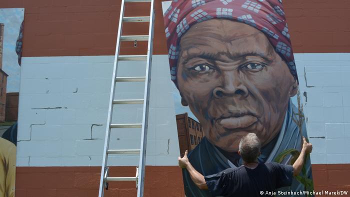 Michael Rosato's murals are gigantic, as can be seen in this photo showing him hanging the portrait panel of Harriet Tubman