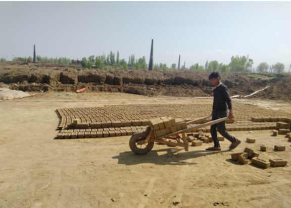 A child moves kacha bricks in a hand cart for the preparation of their temporary accommodation inside the brick kiln premises.