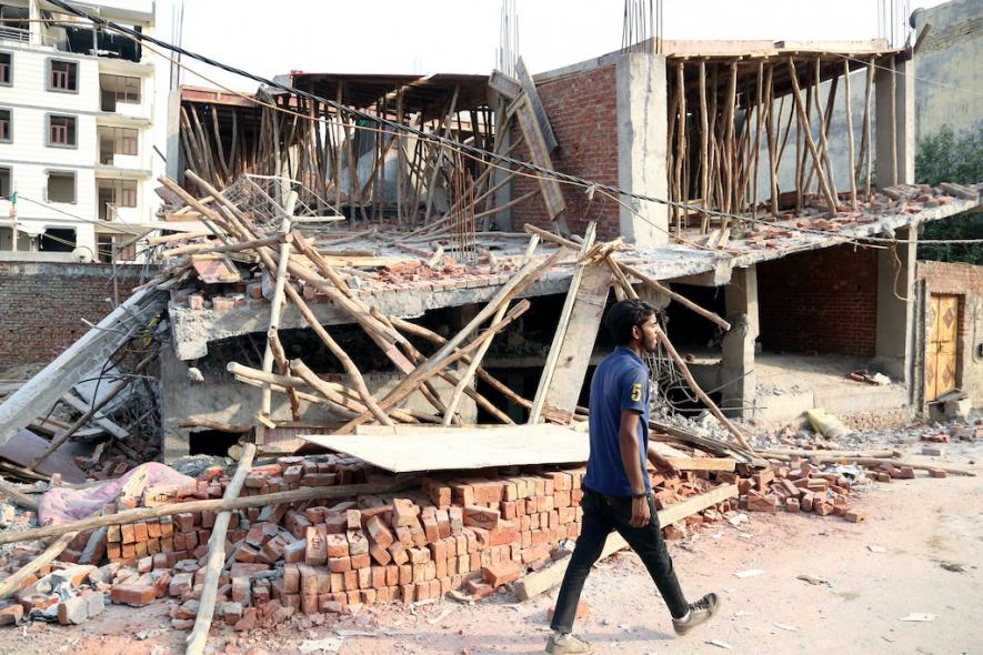 A man walks past demolished structure after a demolition drive