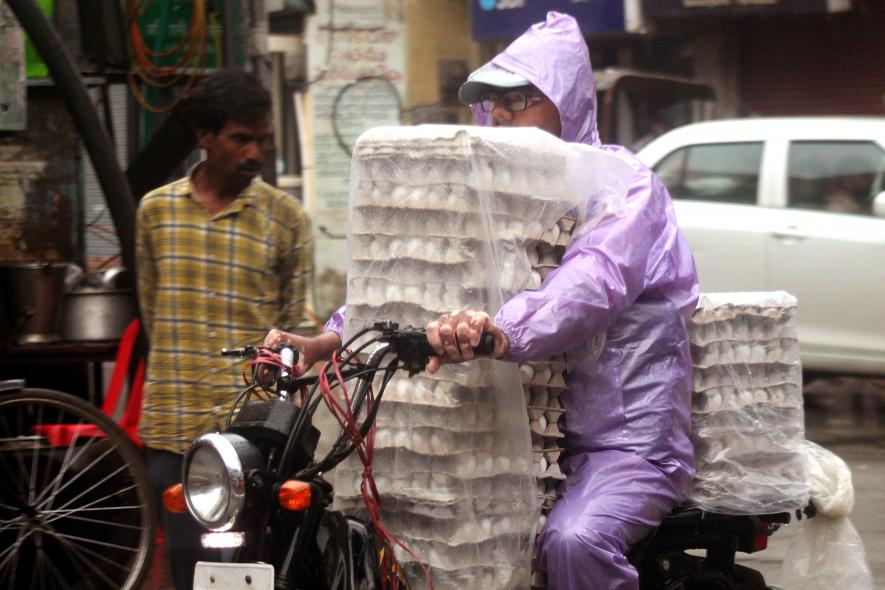 A vendor carries the pile of eggs covered in the plastic sheets on his bike