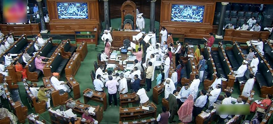 Opposition MPs holding placards stage a protest over inflation, 5% GST on essential items and other issues in the Well of Lok Sabha 