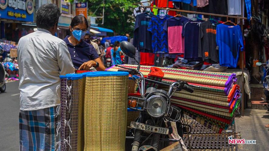 A vendor sells mats on his two-wheeler.