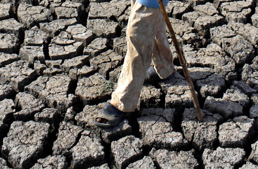 A man walks on a parched bed in drought-affected Vena Dam on a hot summer day in Nagpur