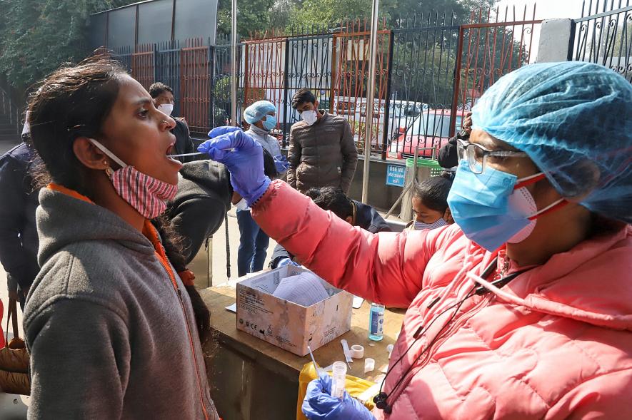 A healthcare worker collects a swab sample of a passenger for the COVID-19 test as the country sees an Omicron-driven Coronavirus surge, at New Delhi Railway station