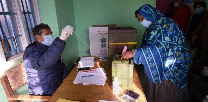 A woman casts her vote for the first phase of the District Development Council (DDC) elections, at Gund in Ganderbal district of central Kashmir.