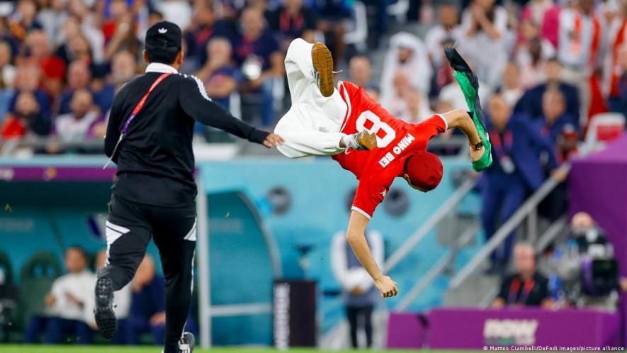 A Tunisia fan runs onto the field in Qatar grasping a Palestine flag.