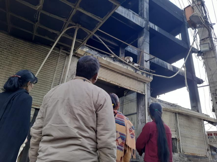 Two mothers, a father, and a sister stare into the dead building that took the lives of their loved ones.