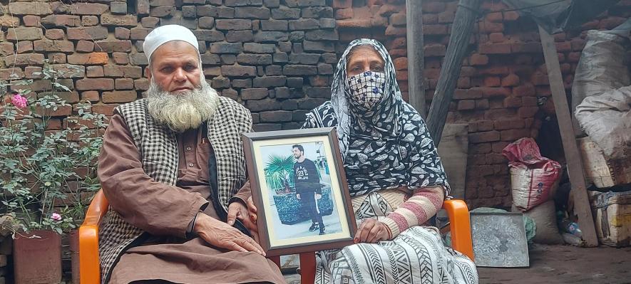 Shamshad Ahmad and his wife hold a photo of their son Shadab Ahmad.