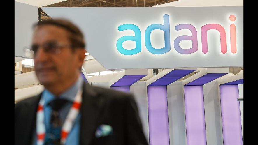 An official walks past the stall of Adani Defence and Aerospace during the inauguration of Aero India 2023, at Yelahanka air base in Bengaluru, Monday, Feb. 13, 2023. / Image Courtesy: PTI