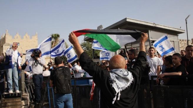 A Palestinian flag raised in front of Jewish settlers performing their provocative 'flag march'. (Photo: Oren Ziv via Activestills.org)