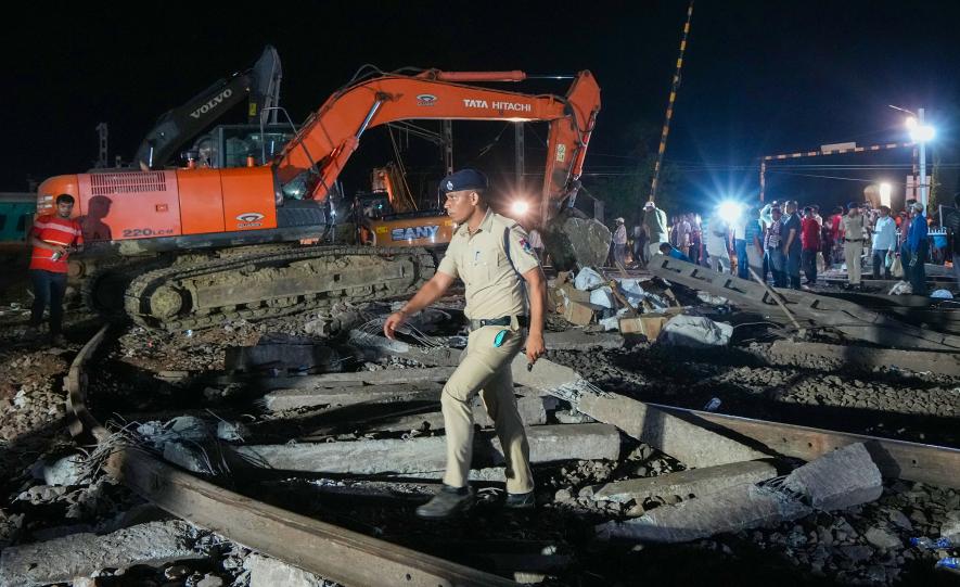 A police pesonnel crosses the mangled railway tracks during a rescue and search operation after the triple train mishap that claimed at least 261 people and left over 900 injured, in Balasore district, Odisha, Saturday, June 3, 2023.