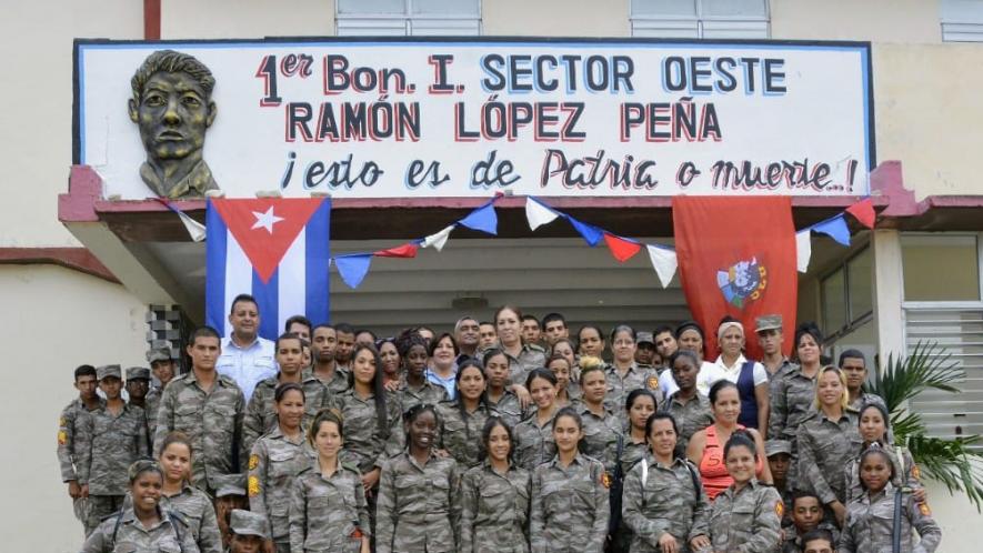 Cuba soldiers in the Frontier Brigade that defends Cuba outside of the US-occupied Guantanamo Bay Naval Base. Soldiers stand outside a sign commemorating Ramon Lopez Peña, a Cuban Frontier Brigade soldier martyred by US forces (Photo: Tony Hernández Mena/Cuban Parliament)
