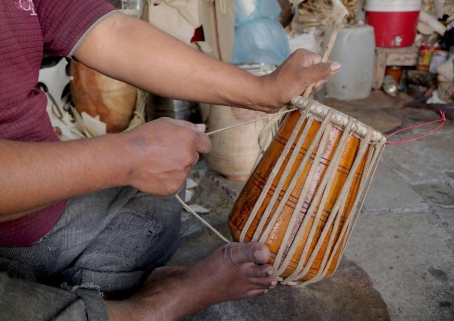 Barri stretches the membrane strips around a tabla.