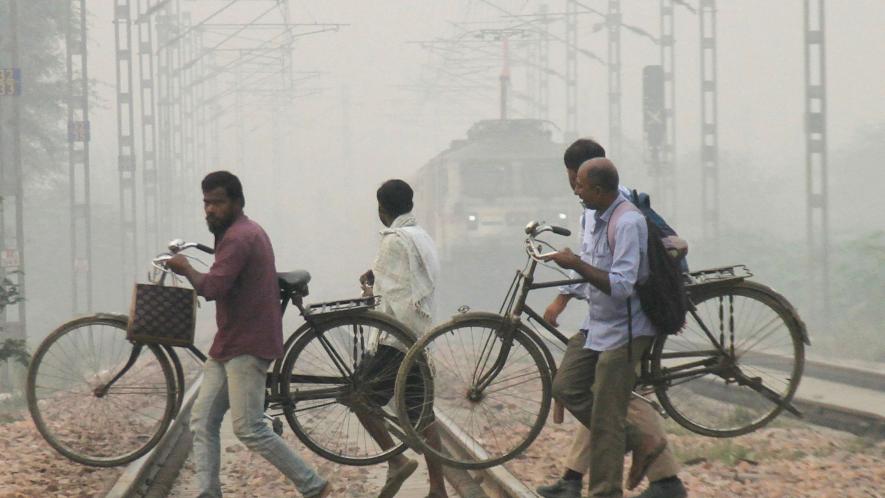 Commuters cross railway tracks amid low visibility due to smog, in Gurugram, Thursday, Nov. 9, 2023.