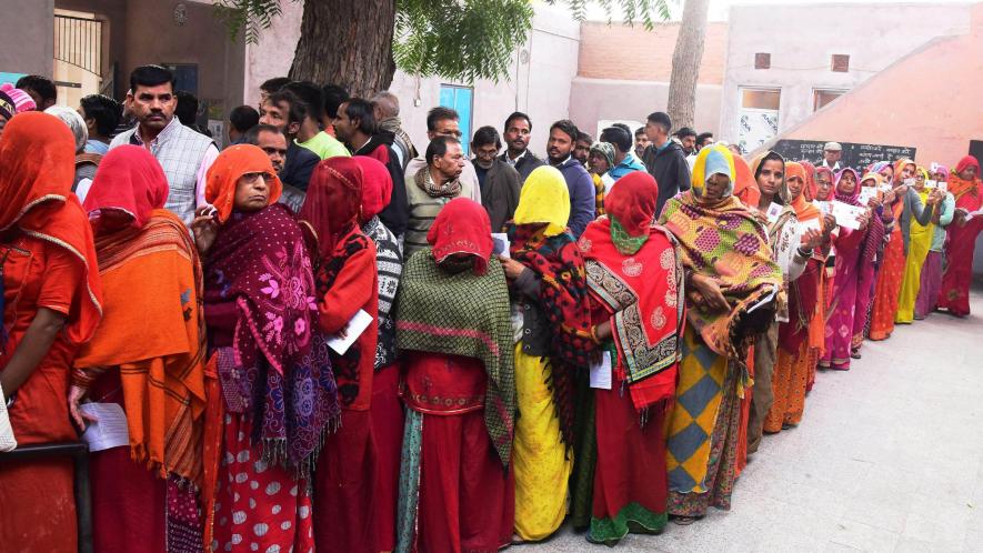 People stand in queues to cast their votes for the Rajasthan Assembly elections, in Bikaner, Saturday, Nov. 25, 2023. 