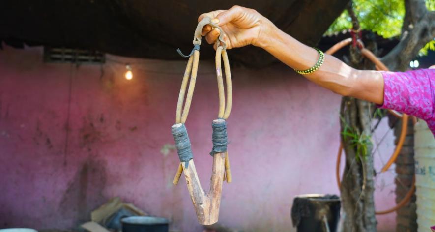 Masabai Kale, a Pardhi woman, holding a sling shot she made to sell in the local fare markets (Photo- Azib Ahmed, 101Reporters)