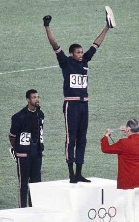 American sprinters Tommie Smith and John Carlos, along with Australian Peter Norman, during the award ceremony of the 200 m race at the Mexican Olympic games. During the awards ceremony, Smith (center) and Carlos protested against racial discrimination: they went barefoot on the podium and listened to their anthem bowing their heads and raising a fist with a black glove. Mexico City, Mexico, 1968.